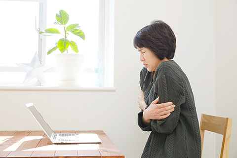 部屋の中で寒そうにする女性 写真