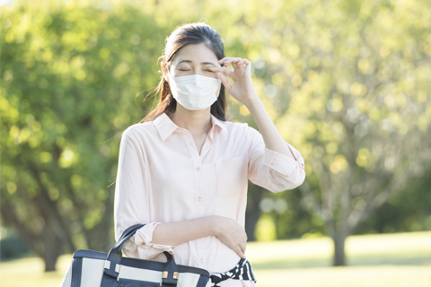 マスクを着けて目をこする女性 写真